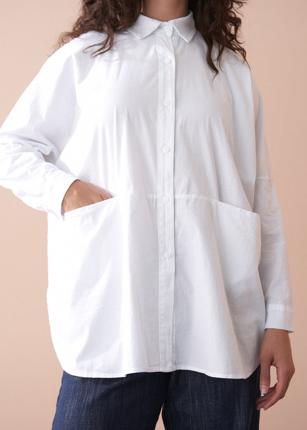 Person wearing a white shirt with a beige background