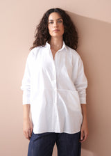 Woman wearing a white shirt against a beige wall