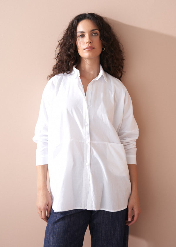 Woman wearing a white shirt against a beige wall
