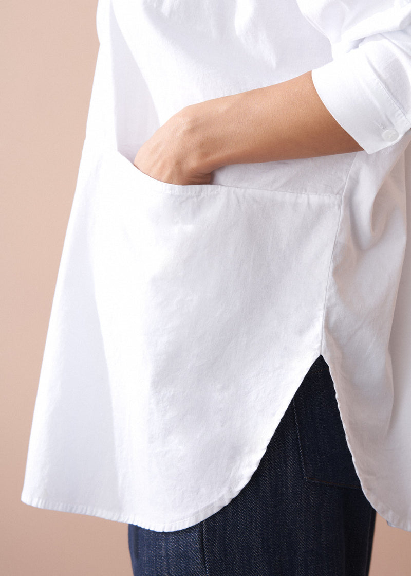 White shirt with rolled-up sleeves worn by a person on a beige background