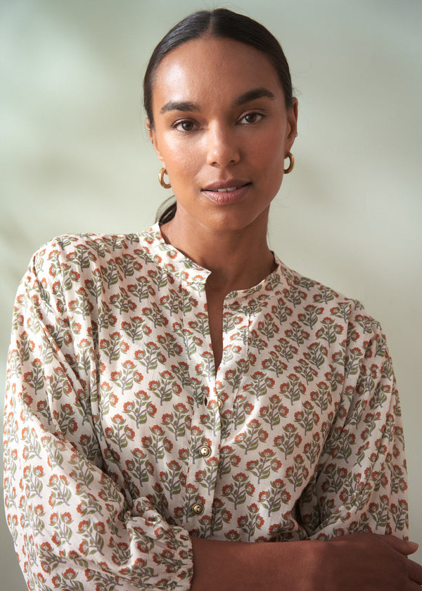 Woman wearing a floral blouse against a plain background