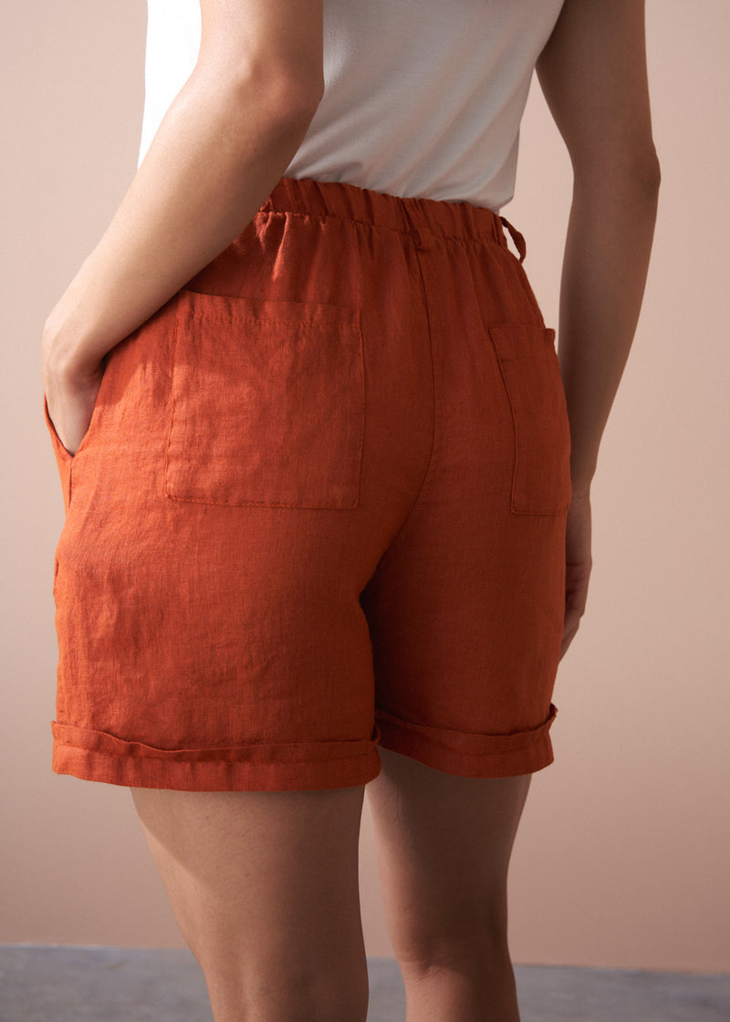 Person wearing orange shorts with a plain background