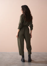 Woman wearing a green jumpsuit against a beige background