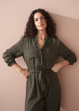 Woman wearing a green jumpsuit against a pink wall