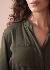 Close-up of a person wearing an olive green shirt against a neutral background