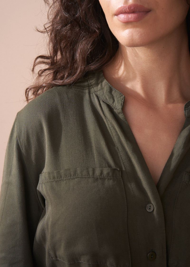 Close-up of a person wearing an olive green shirt against a neutral background