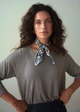 Woman wearing a striped shirt with a neckerchief against a plain background