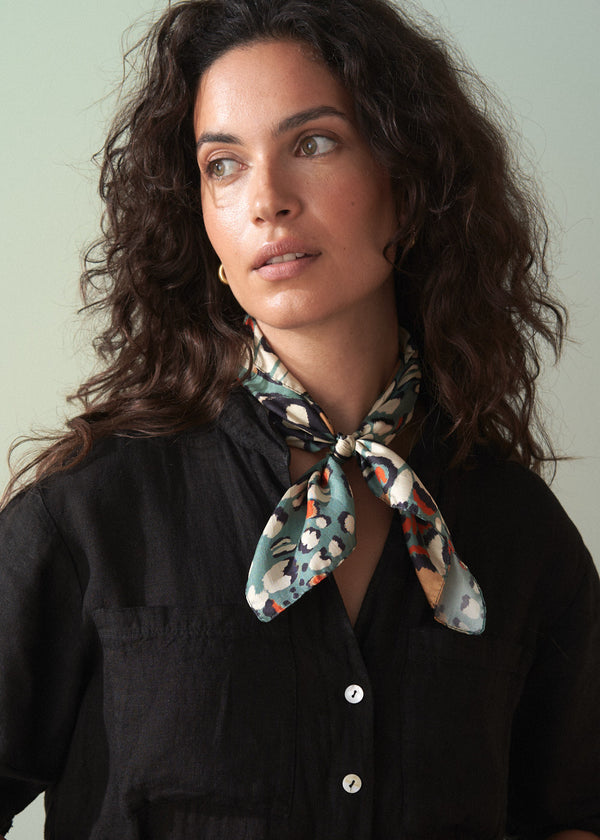 Woman wearing a floral scarf around her neck against a plain background
