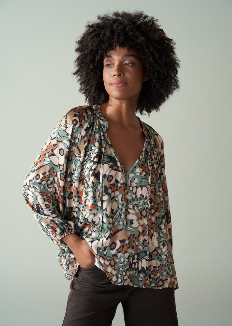 Woman wearing a patterned blouse against a plain background