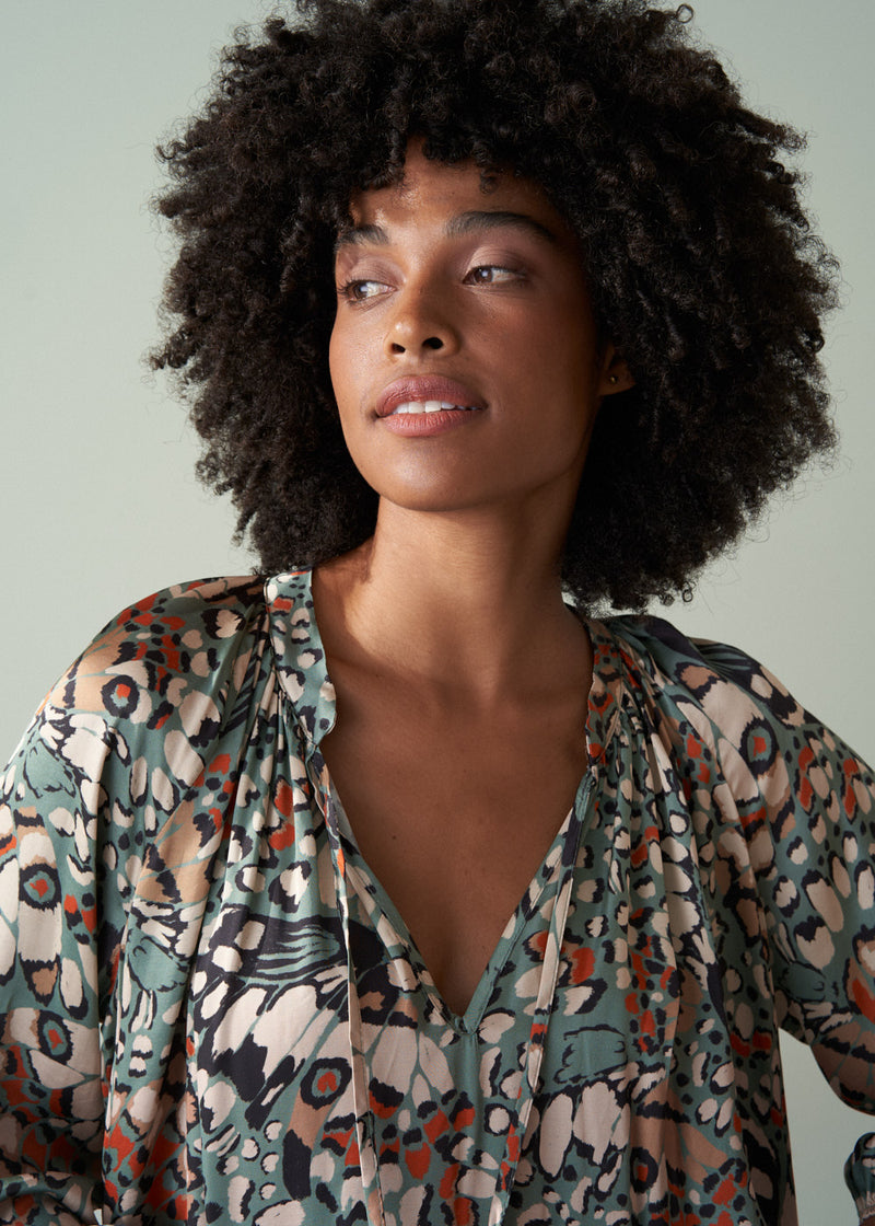 Woman wearing a patterned blouse against a plain background