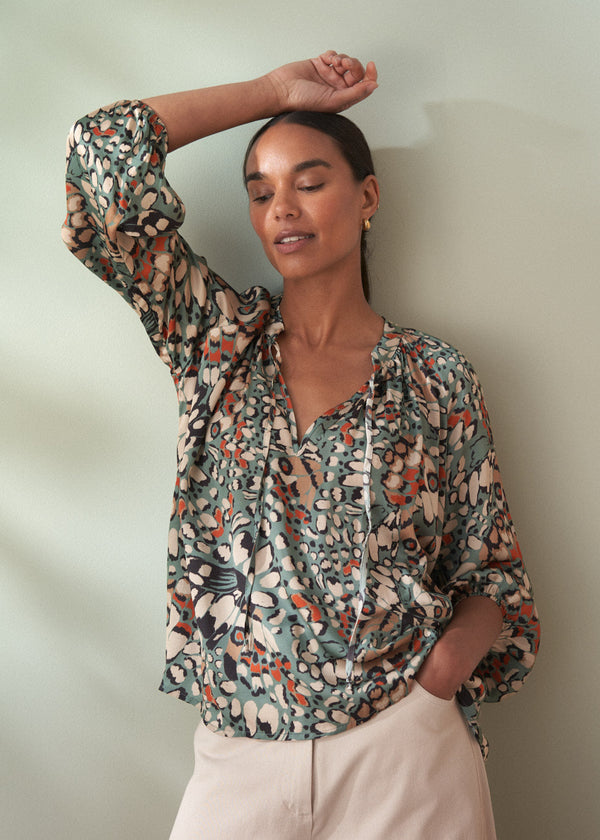Woman wearing a patterned blouse against a plain background