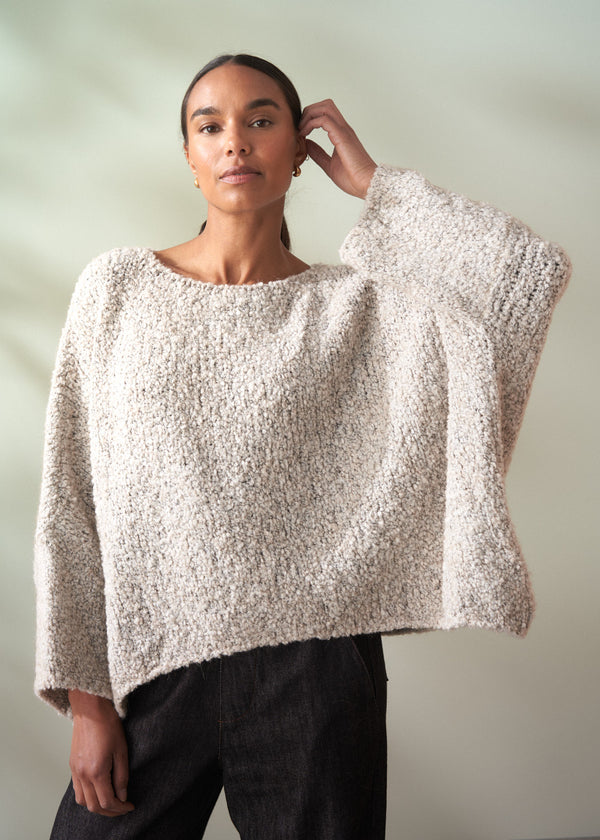 Woman wearing a textured beige sweater against a plain background