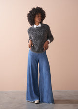 Woman wearing a dark grey fluffy textured sweater with sequin detail.
