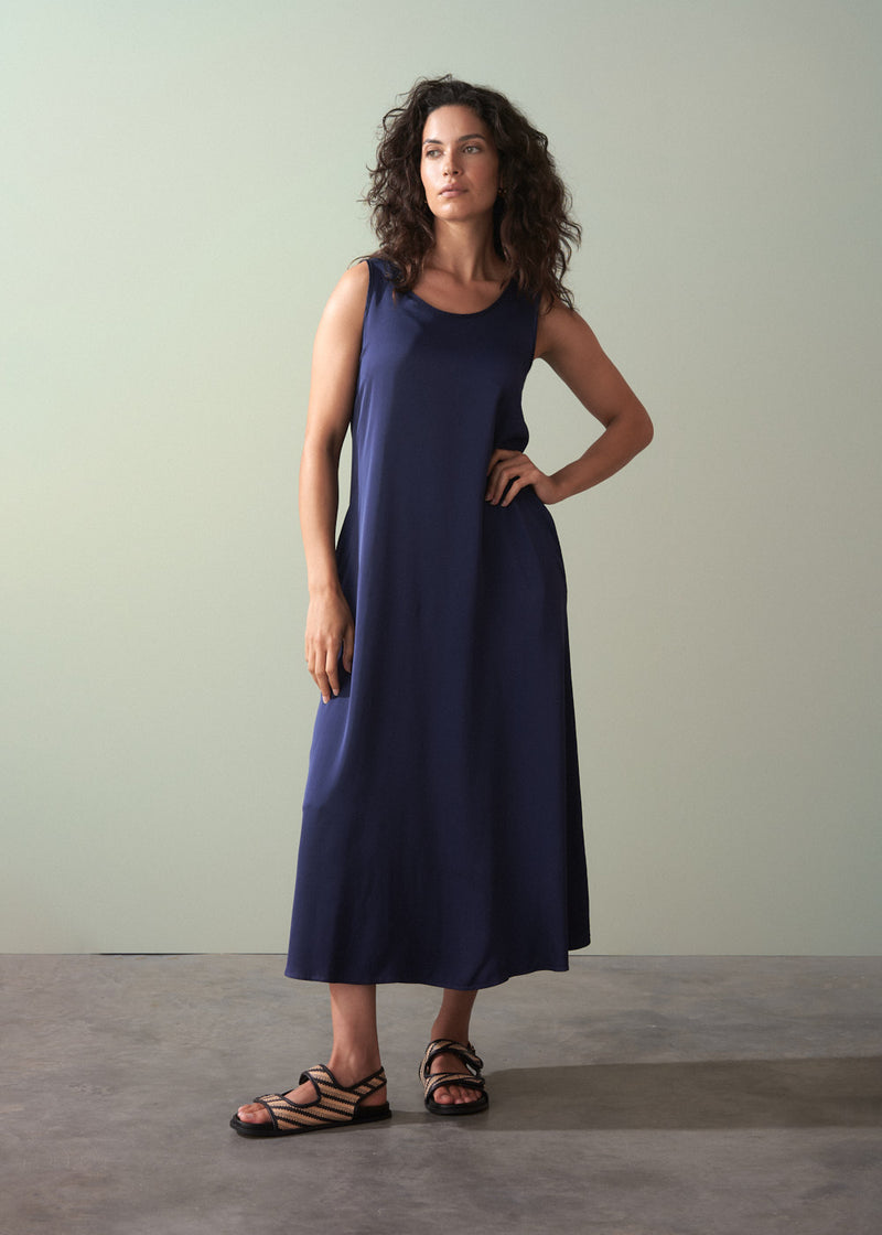 Woman wearing a navy blue sleeveless dress against a plain background