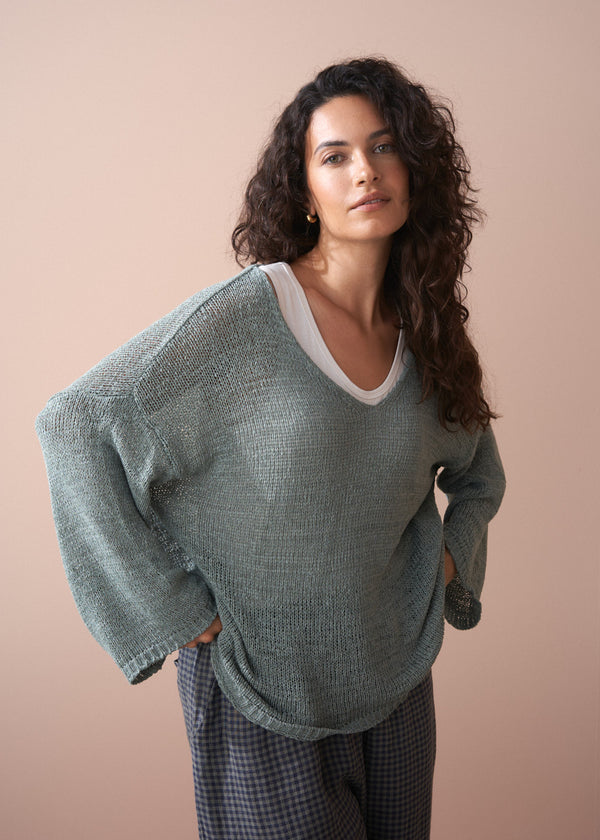 Woman wearing a green sweater against a beige background