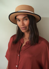Woman wearing a straw hat with a white band against a plain background