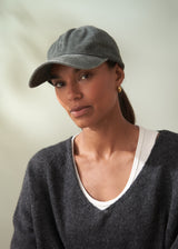 Woman wearing a gray cap and dark sweater against a neutral background