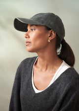 Woman wearing a gray cap and dark sweater against a neutral background
