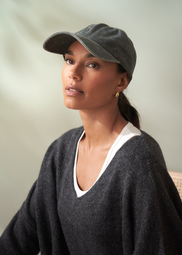 Woman wearing a gray cap and dark sweater against a neutral background