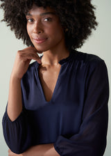 Woman wearing a navy blue blouse against a plain background
