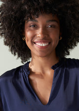 Woman with an afro wearing a navy blue top against a neutral background