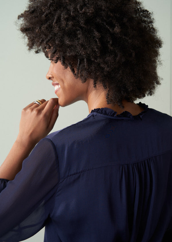Woman wearing a navy blue blouse against a light green background
