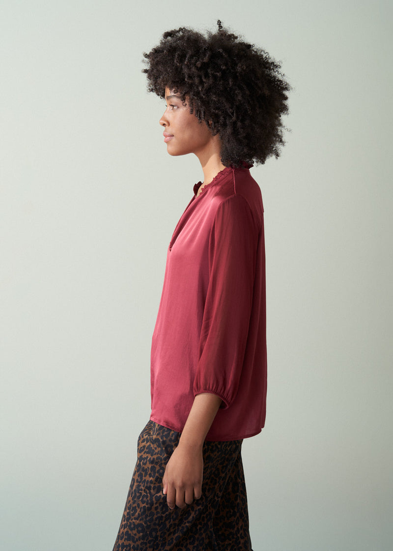 Woman wearing a red blouse against a plain background