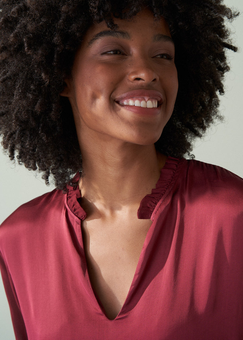 Woman wearing a pink blouse against a neutral background