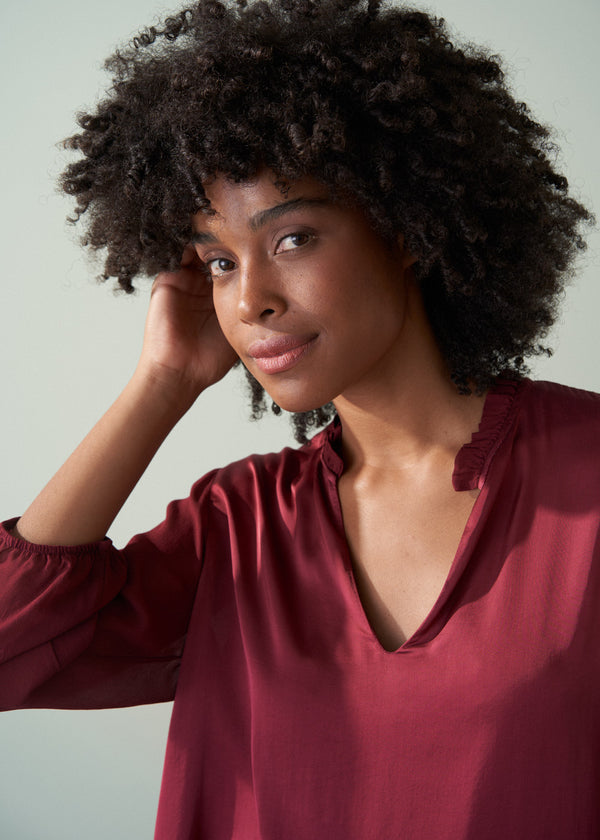Woman wearing a burgundy top with a plain background