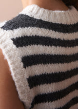 Close-up of a person wearing a black and white striped sleeveless sweater.