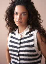 Woman wearing a black and white striped sleeveless knitted vest against a beige background