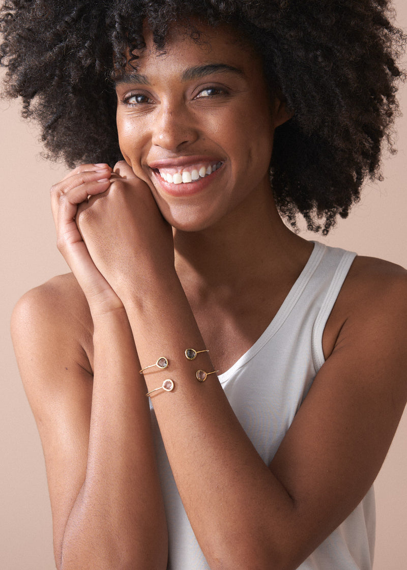 Woman wearing gold bracelets on a beige background