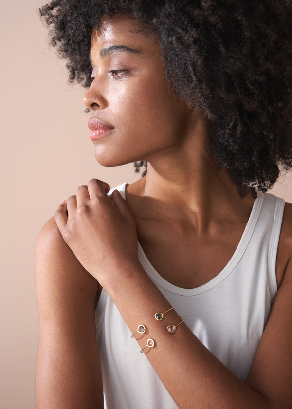 Woman wearing gold bracelets on a beige background