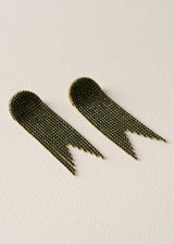 A pair of dangling fringe earrings made of small metallic beads, arranged on a textured off-white background.