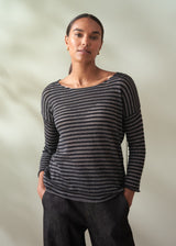 Woman wearing a black and gray striped sweater against a plain background