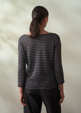 Person wearing a black and gray striped shirt against a plain background
