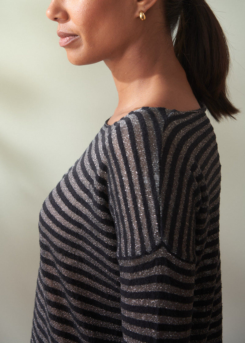 Woman wearing a black and silver striped top with a blurred background