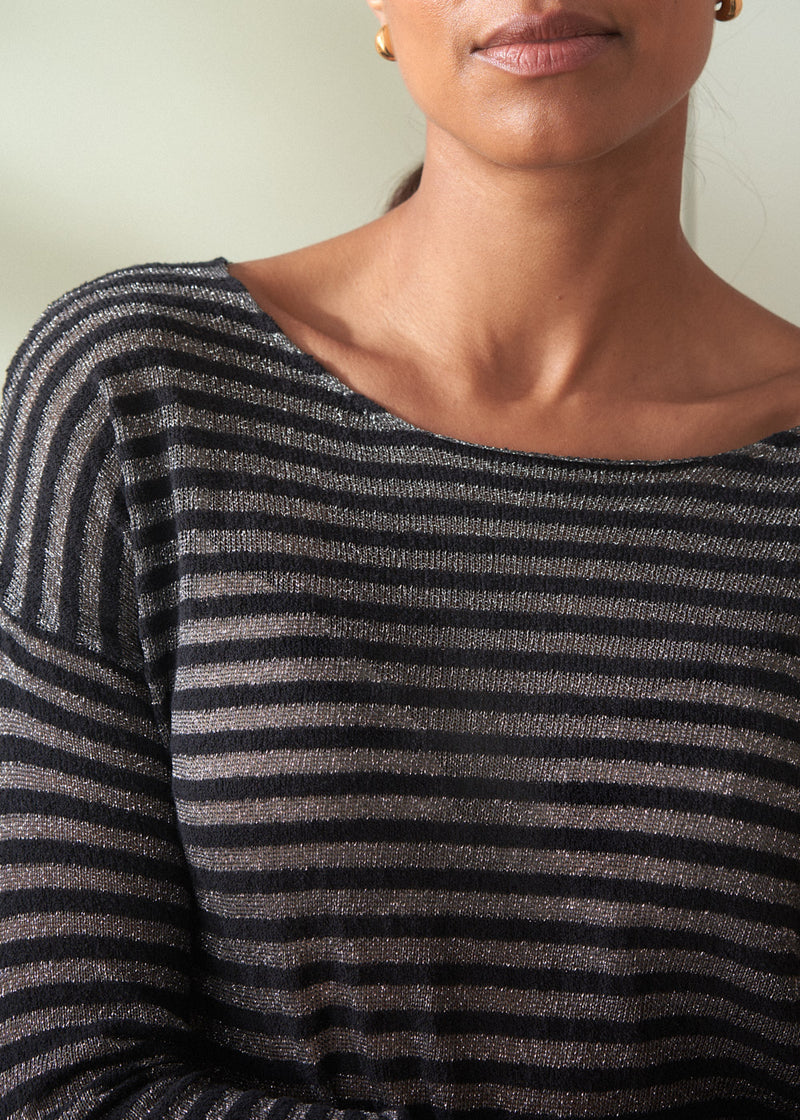 Person wearing a black and gray striped sweater against a neutral background