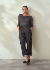 Woman wearing a striped sweater and dark pants against a plain background
