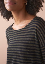 Woman wearing a striped gold and black top against a beige background