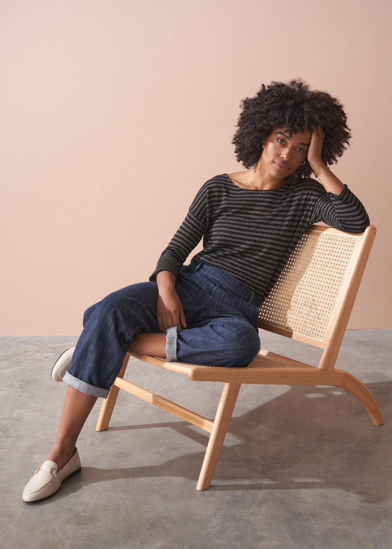 Woman wearing a striped gold and black top against a beige background