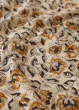 Close-up of floral patterned fabric with orange, black, and white colors.