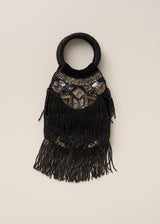 A black beaded handbag with a circular top handle, a geometric patterned chest panel, and long fringe, shown against a plain light beige background.