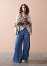 Woman wearing a beige sweater and blue jeans against a beige background