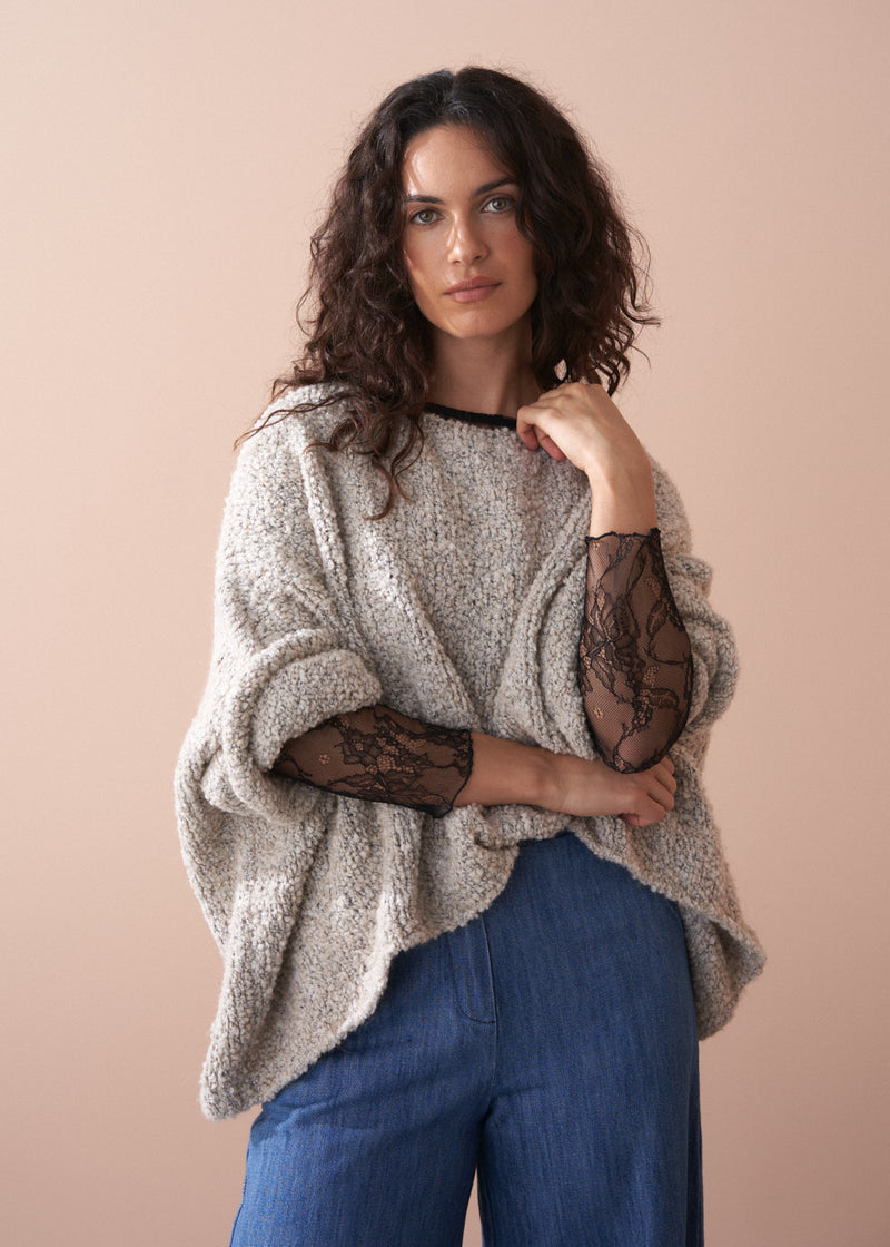Woman wearing a black lace top against a beige background