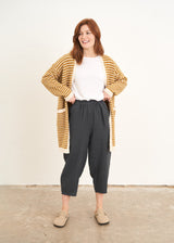 A model wearing a yellow and white stripe cardigan over a white top with blue grey cropped trousers and taupe clogs