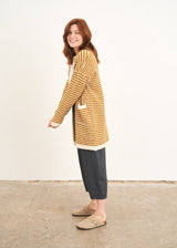 A model wearing a yellow and white stripe cardigan over a white top with blue grey cropped trousers and taupe clogs