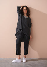 Woman wearing a striped long sleeve shirt and black drawstring trousers against a beige background