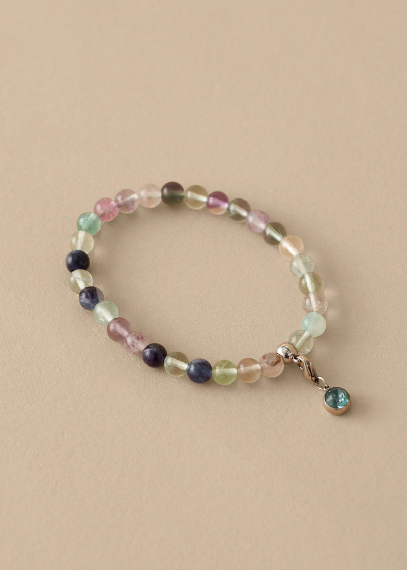 Multicolored beaded bracelet with a charm on a beige background