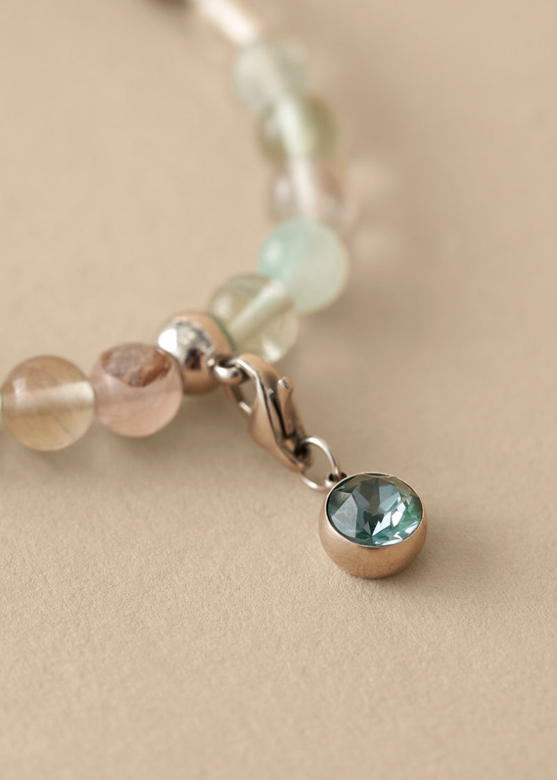 Close-up of a bracelet with beaded charm on a beige background